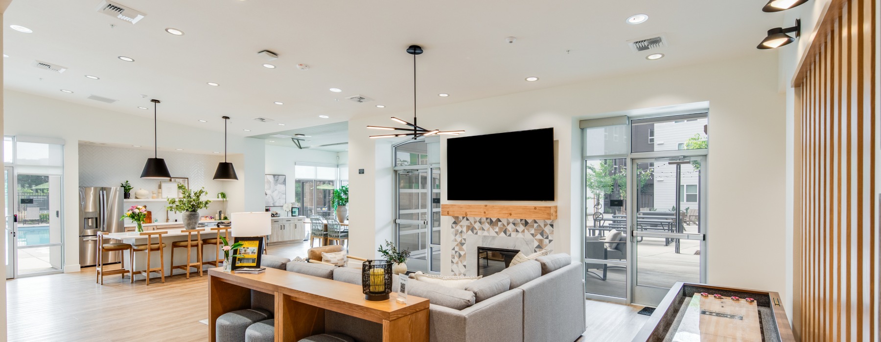 Spacious and well lit living room with wood floors and a large window with access to the kitchen